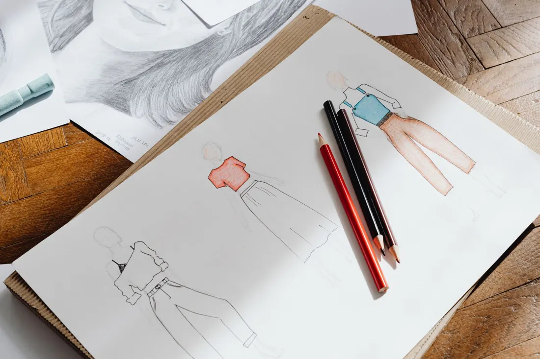 Fashion sketches and pencils on a garment design worktable